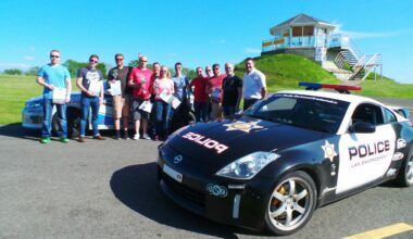 A group of people standing behind a rally spec Nissan 350Z