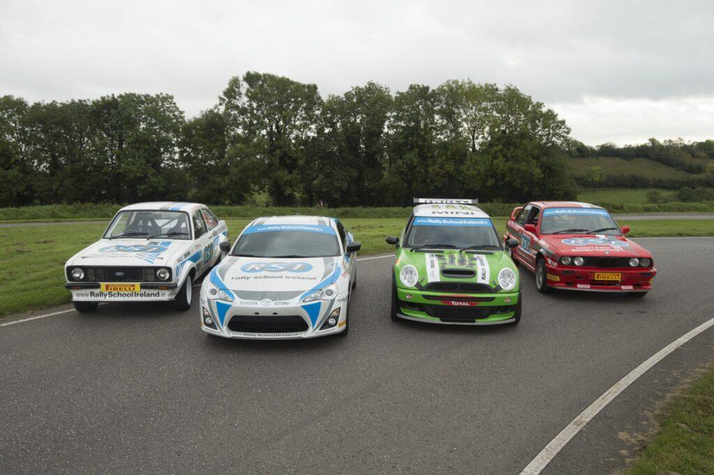 Four rally cars on track at Rally School Ireland, showcasing diverse models and designs against a lush green backdrop.