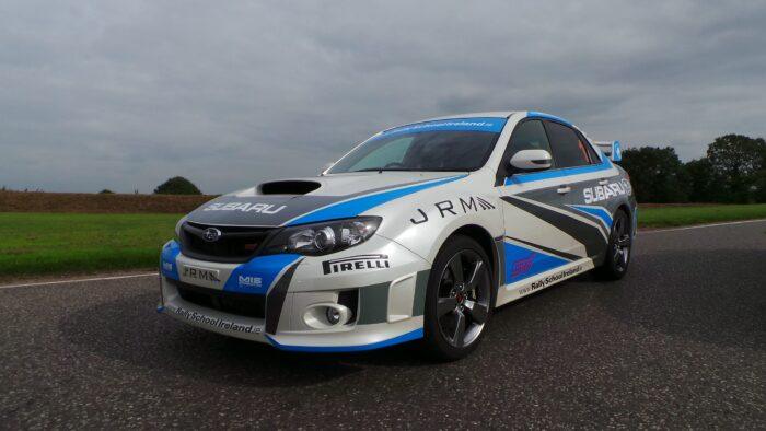 Subaru rally car with blue and white livery on a road, showcasing sporty design and performance.