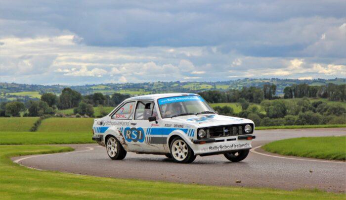 Rally car speeding on a scenic countryside road, showcasing Rally School Ireland driving skills and dynamic motion.