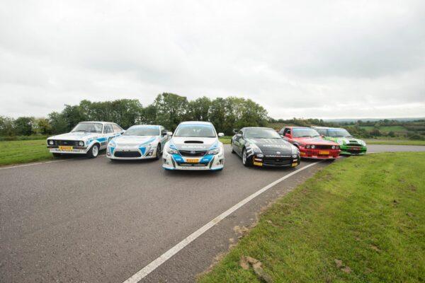 Lineup of colorful rally cars on a track, showcasing diverse styles and models ready for an exciting race.